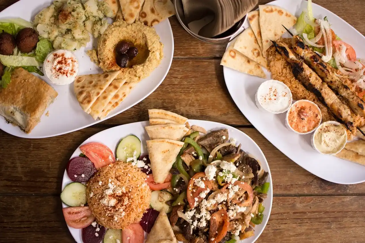 Greek food spread in Corfu with souvlaki, pita, dips and grilled meat on a wooden table.