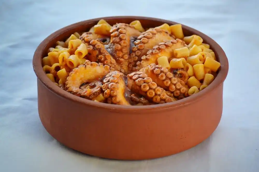 Greek octopus served with pasta in a clay bowl, typical seafood dish in Corfu.