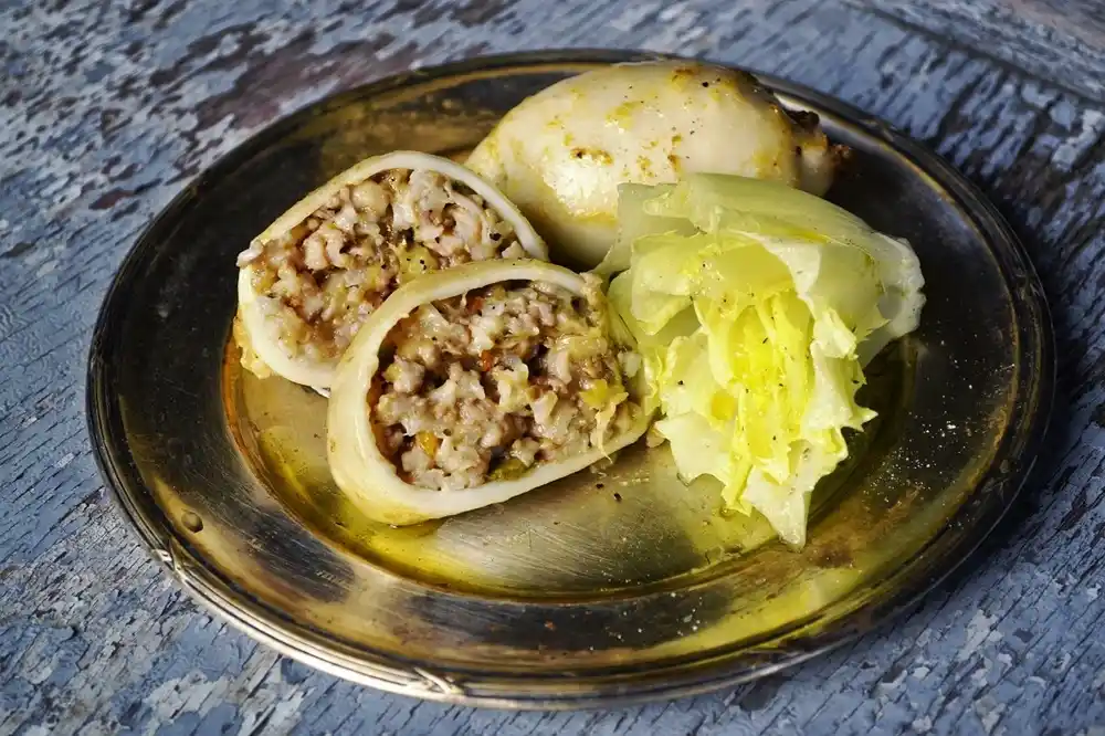 Greek stuffed Calamari filled with rice and herbs served with vegetables on a plate.