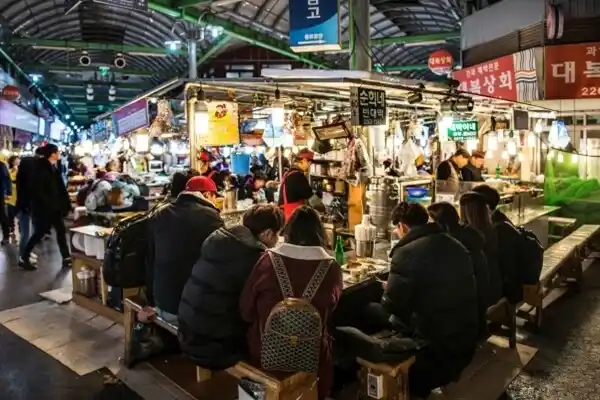 Pengunjung makan di warung street food di Gwangjang Market di Seoul.