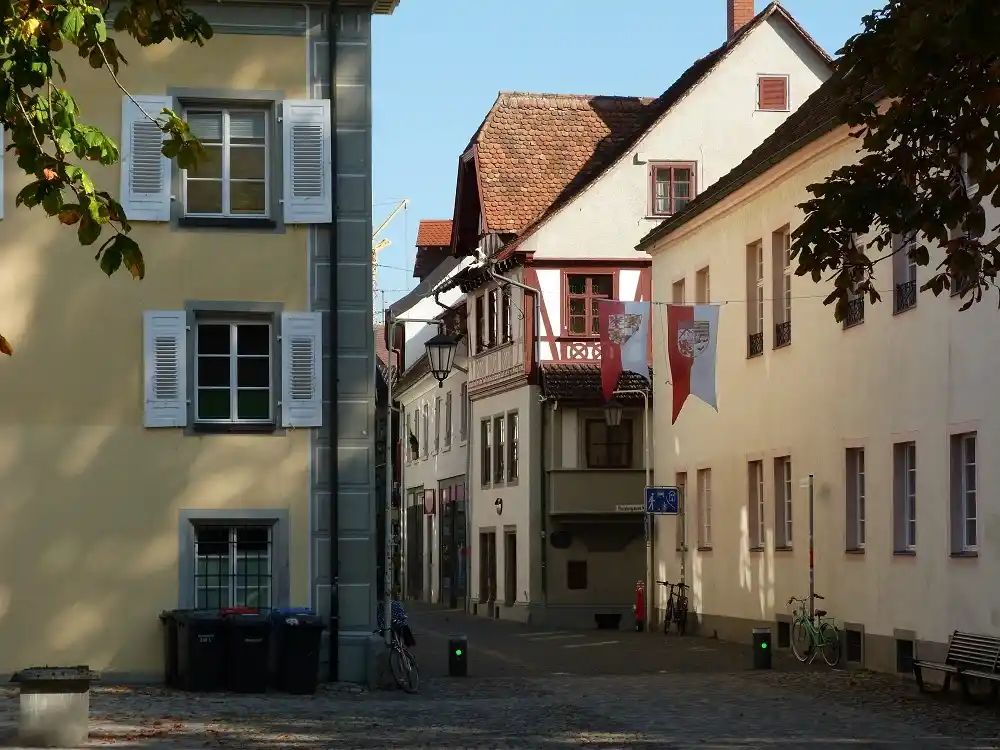 Narrow cobbled street with historic houses and flags in Konstanz.