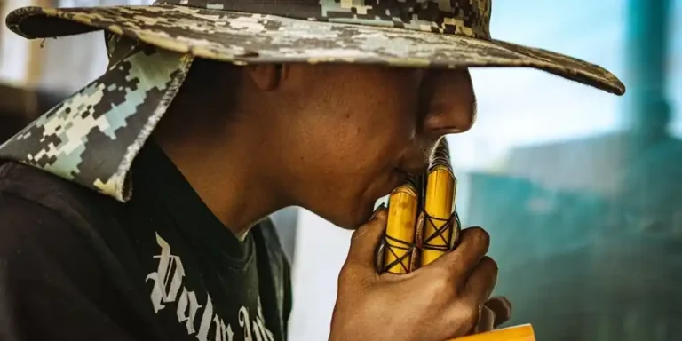 Close-up of a man playing traditional Andean pan flutes with a city background in Peru.