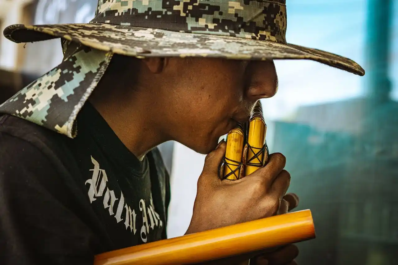 Close-up of a man playing traditional Andean pan flutes with a city background in Peru.