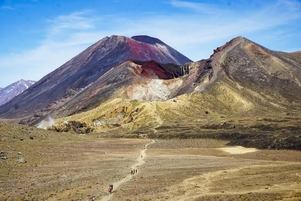 Volcanic peaks and barren terrain in Tongariro National Park, New Zealand, with hiking trails leading towards Mount Ngauruhoe, the filming location for Mount Doom.