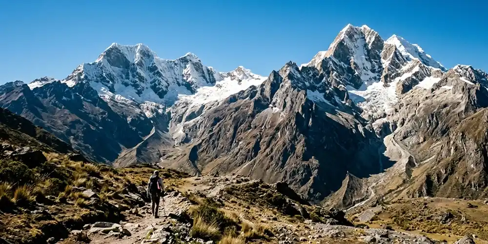 Sharp Andean mountain peaks in Peru under clear morning light with blue sky and light snow.